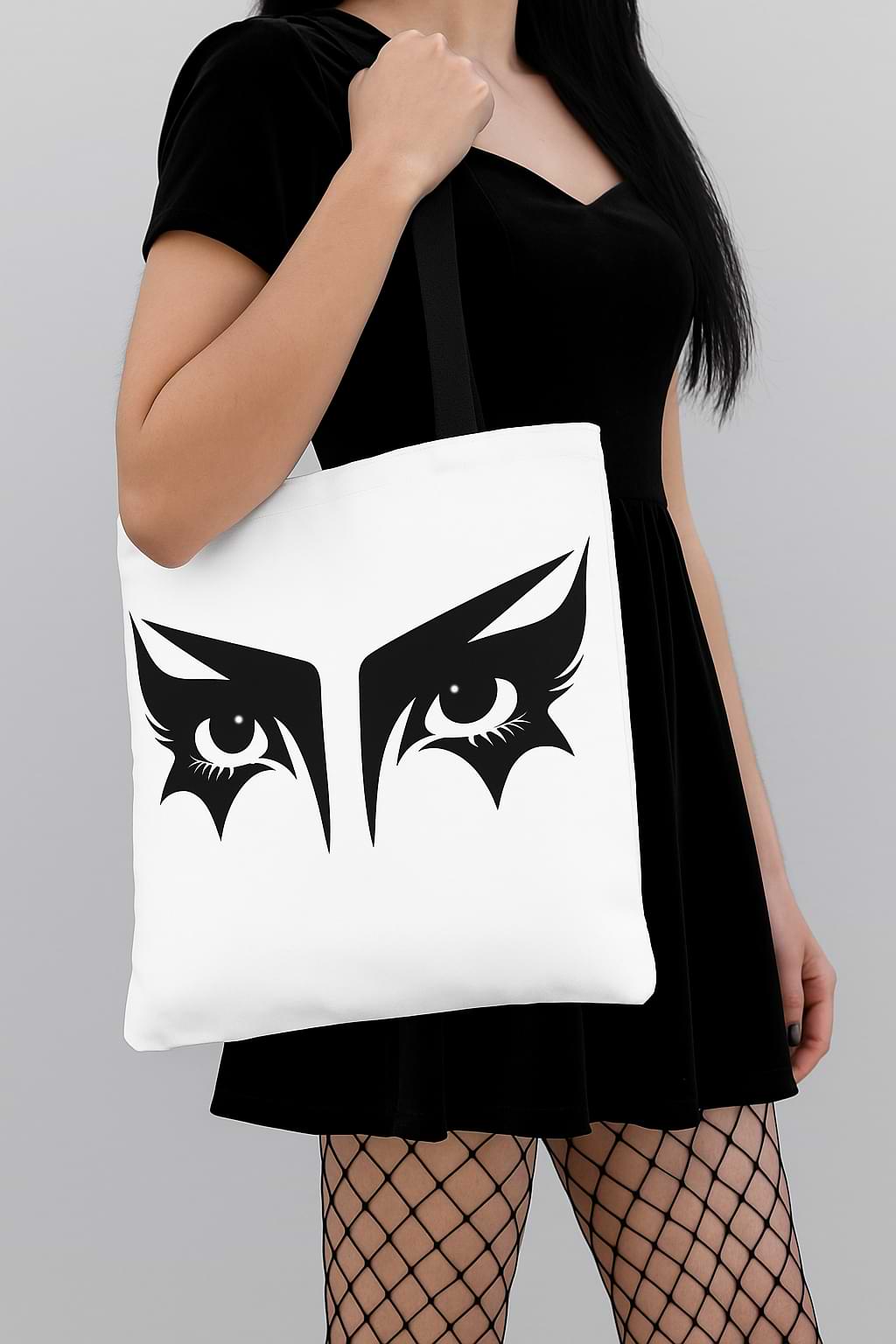 Goth girl carrying a gothic tote bag that has an illustration of trad goth makeup against a white background.