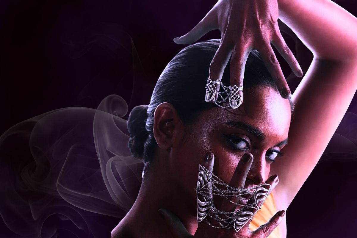 Close-up of a gothic bride wearing webbed silver rings against a dark, misty background