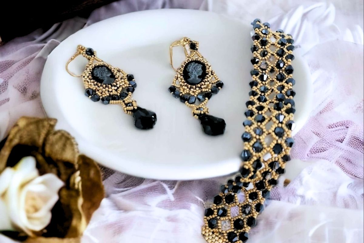 Gold and black Swarovski beaded bracelet with matching cameo earrings on white dish