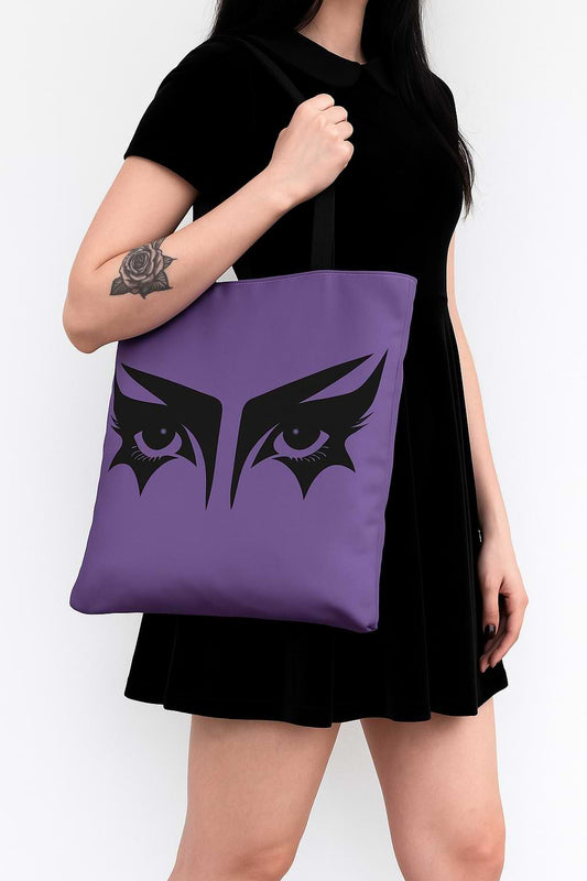 Goth girl carrying a gothic tote bag that has an illustration of trad goth makeup against a lilac background.